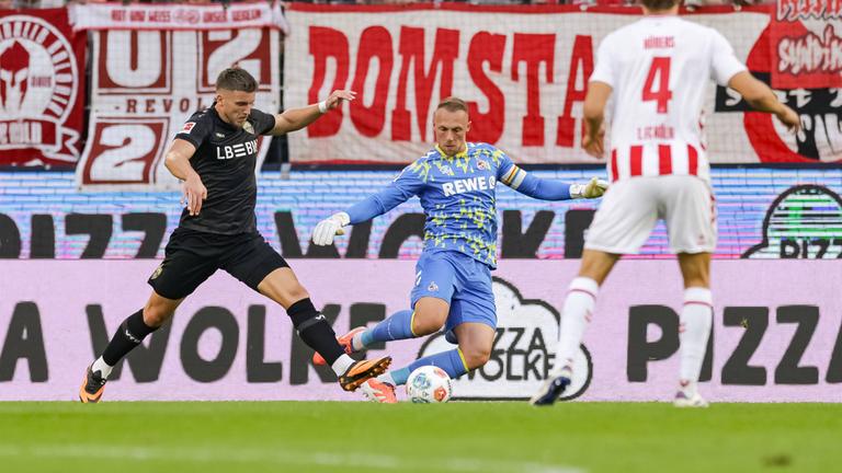 Kölns Torwart Marvin Schwäbe foult Stuttgarts Ermedin Demirovic.