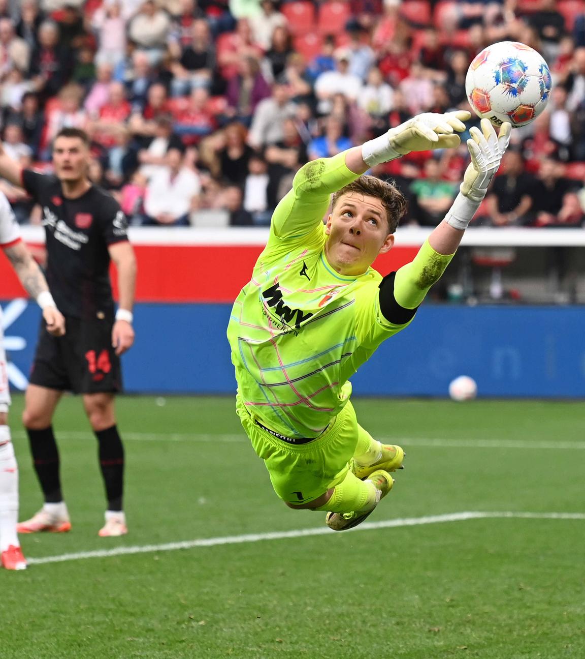 Parade von Torwart Finn Dahmen (FC Augsburg) am 18.04.2026 in Leverkusen.