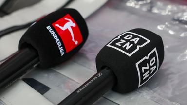 Ein Mikrofon des Streaminganbieters DAZN und ein Bundesliga-Mikro liegen auf einem Tisch.