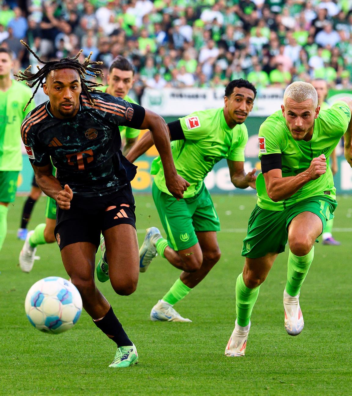 Bayern Münchens Sacha Boey in Aktion gegen Wolfsburgs Jakub Kaminski beim Auftaktspiel der Bundesliga.