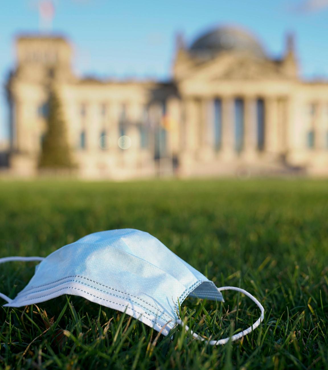 Eine OP-Maske liegt auf der Wiese vor dem Reichstag