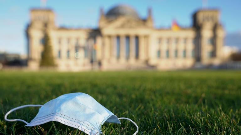 Eine OP-Maske liegt auf der Wiese vor dem Reichstag