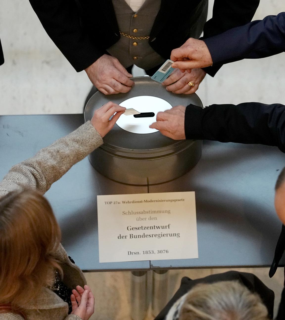 Abgeordnete geben bei einer namentlichen Abstimmung über das Gesetz für einen neuen Wehrdienst ihre Stimmkarten im Bundestag ab.