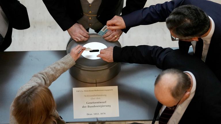 Abgeordnete geben bei einer namentlichen Abstimmung über das Gesetz für einen neuen Wehrdienst ihre Stimmkarten im Bundestag ab.