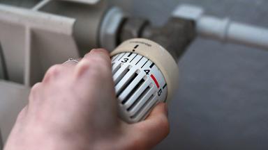 24.02.2026, Berlin: Eine Frau dreht an einem Thermostatregler einer Heizung in einer Wohnung.