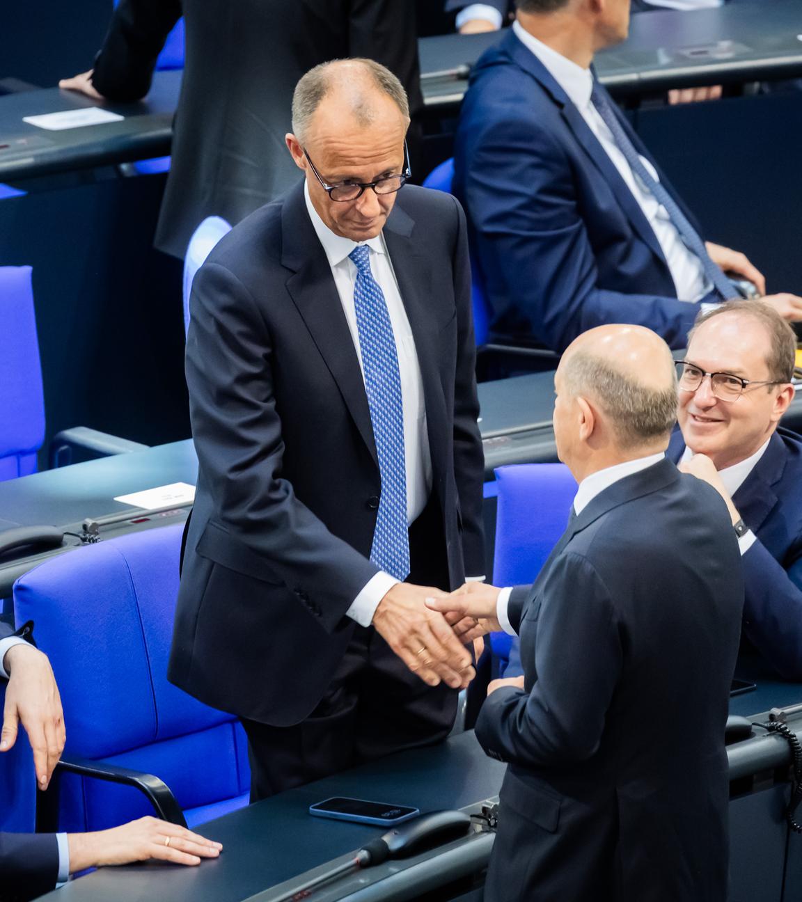 Berlin: Der designierte Bundeskanzler Friedrich Merz (CDU, M oben) und der geschäftsführende Bundeskanzler Olaf Scholz (SPD, unten M) schütteln sich neben Jens Spahn (CDU, l), Vorsitzender der CDU/CSU Bundestagsfraktion, und Alexander Dobrindt (CSU, r), designierter Innenminister, im Bundestag beim zweiten Durchgang der Kanzlerwahl die Hand.