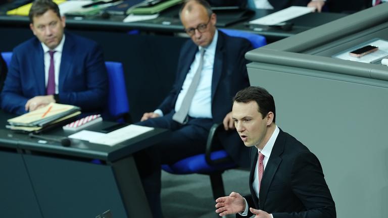 Berlin: Pascal Reddig (CDU, r), Vorsitzender der Jungen Gruppe der Union im Bundestag, spricht in der Sitzung des Bundestags, im Hintergrund sitzen Lars Klingbeil (SPD, l), Bundesminister der Finanzen, und Bundeskanzler Friedrich Merz (CDU). 