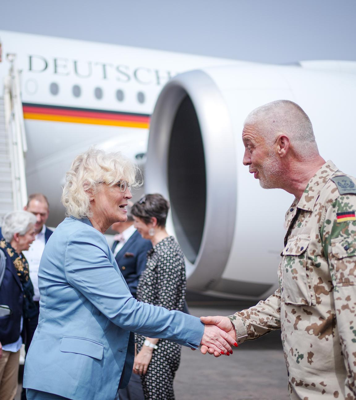 Bundesverteidigungsministerin Christine Lambrecht schütelt die Hand eines Bundeswehr-Soldaten. Sie stehen vor einem Flugzeug. Mali.