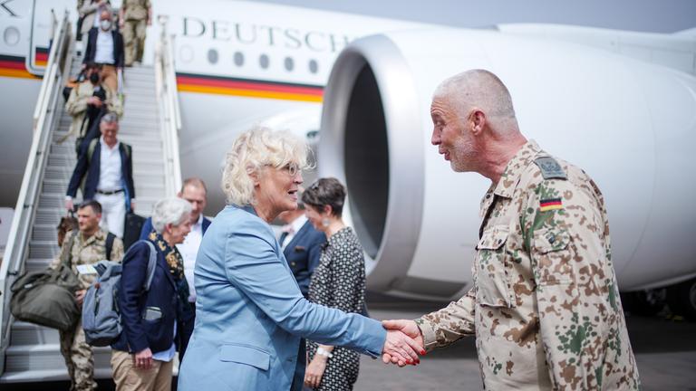Bundesverteidigungsministerin Christine Lambrecht schütelt die Hand eines Bundeswehr-Soldaten. Sie stehen vor einem Flugzeug. Mali.