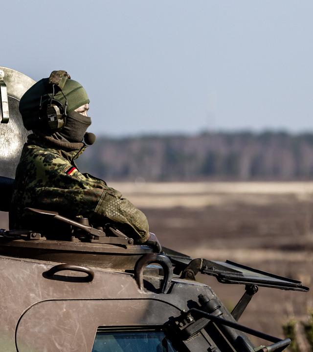 Bundeswehr-Soldatin blickt oben aus einem Panzer.