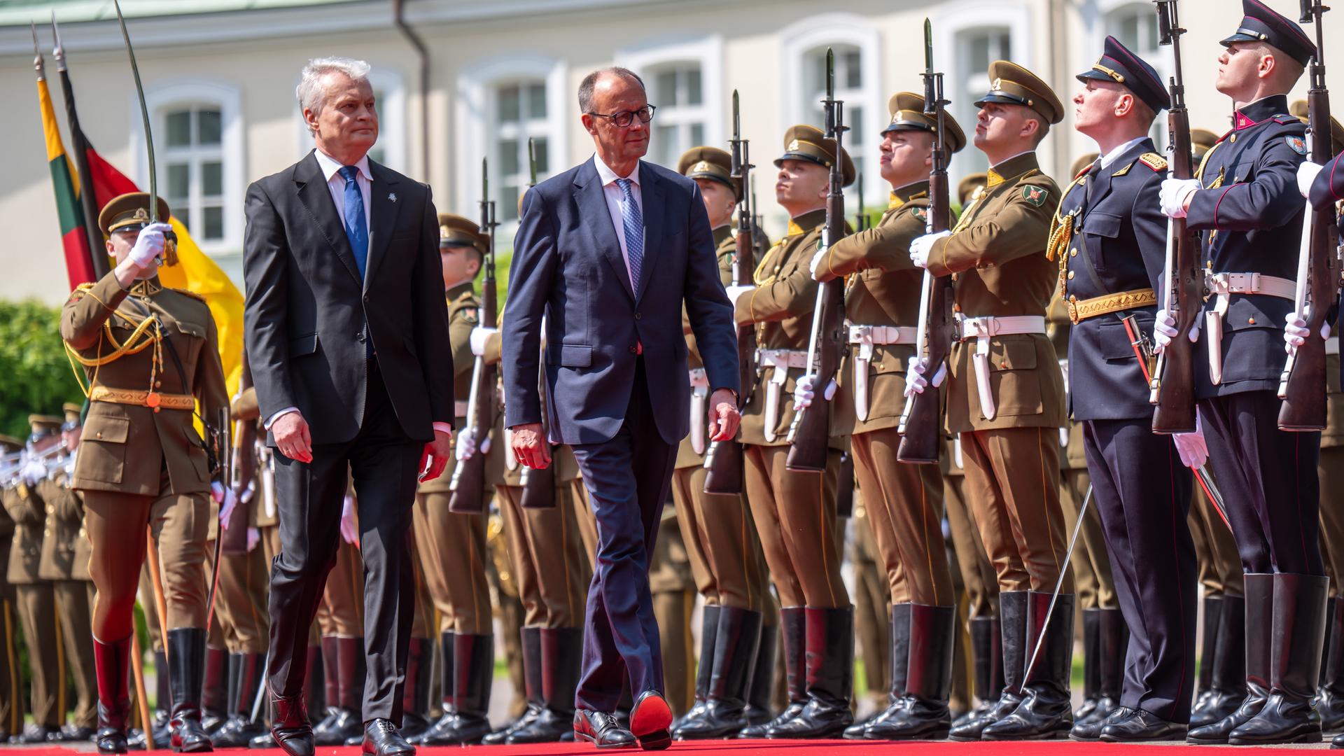 Friedrich Merz und Gitanas Nauseda, Präsident von Litauen, laufen auf rotem Teppich vor Soldaten entlang