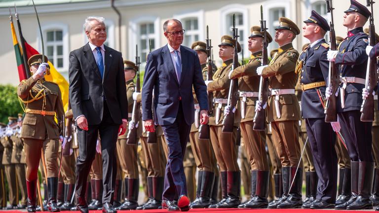 Friedrich Merz und Gitanas Nauseda, Präsident von Litauen, laufen auf rotem Teppich vor Soldaten entlang