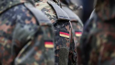Soldaten tragen Deutschlandflaggen auf ihrer Uniform.