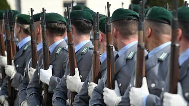 Soldatinnen und Soldaten der Bundeswehr stehen für eine Zeremonie mit Gewehren in einer Reihe