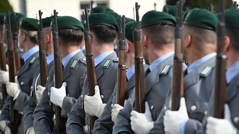 Soldatinnen und Soldaten der Bundeswehr stehen für eine Zeremonie mit Gewehren in einer Reihe