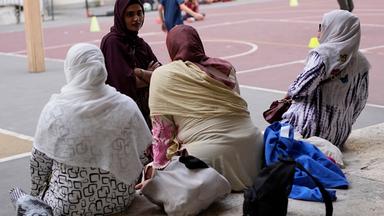 Eine italienische Staatsbürgerin bangladeschischer Herkunft (oben links), unterhält sich mit anderen Müttern, während sie am Donnerstag, dem 24. September 2026, vor einer Schule im Zentrum von Rom auf das Ende des Sportunterrichts warten.