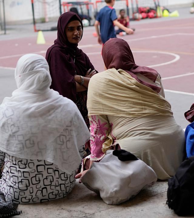 Eine italienische Staatsbürgerin bangladeschischer Herkunft (oben links), unterhält sich mit anderen Müttern, während sie am Donnerstag, dem 24. September 2026, vor einer Schule im Zentrum von Rom auf das Ende des Sportunterrichts warten.