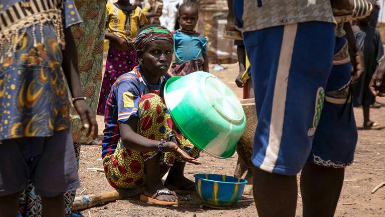 Eine vertriebene Frau hält eine Plastikschüssel im Flüchtlingslager Torodi in Dori, Burkina Faso