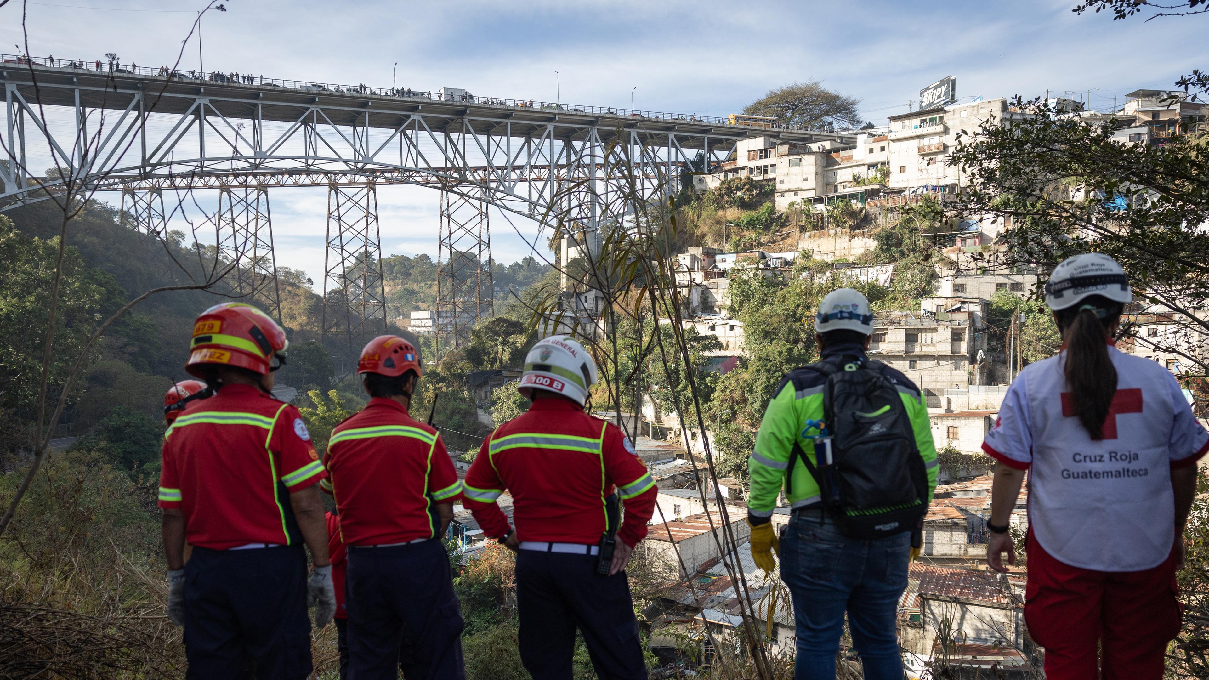 Mitglieder des Hilfskorps betrachten den Grund einer Schlucht, in die ein Bus gestürzt ist, am Rande von Guatemala-Stadt, Guatemala, 10.02.2025.