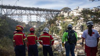 Mitglieder des Hilfskorps betrachten den Grund einer Schlucht, in die ein Bus gestürzt ist, am Rande von Guatemala-Stadt, Guatemala, 10.02.2025.