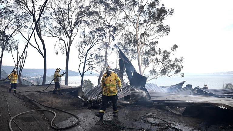 Feuerwehrleute bekämpfen einen Buschbrand, der sich am 06.12.2025 in der Region Koolewong an der Central Coast in New South Wales (NSW), Australien, ausbreitet. 