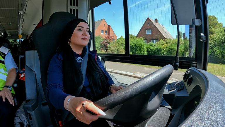 Busfahrerin Elham sitzt am Steuer eines Busses.