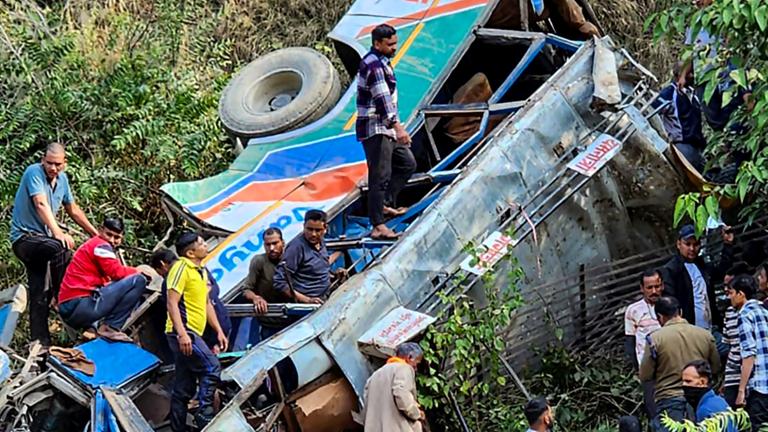 Menschen an der Unfallstelle eines Busses, der in eine Schlucht gestürzt ist.