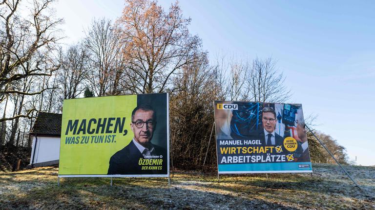 Wahlplakate der Grünen mit Spitzenkandidat Cem Özdemir neben CDU-Plakaten mit Manuel Hagel an einer Straße in Villingen-Schwenningen vor der Landtagswahl in Baden-Württemberg.