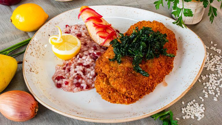 Putenschnitzel mit Camenbert gefüllt, mit frittierter Petersilie getoppt, daneben Preiselbeer-Risotto und gebratene Birnenscheibe.