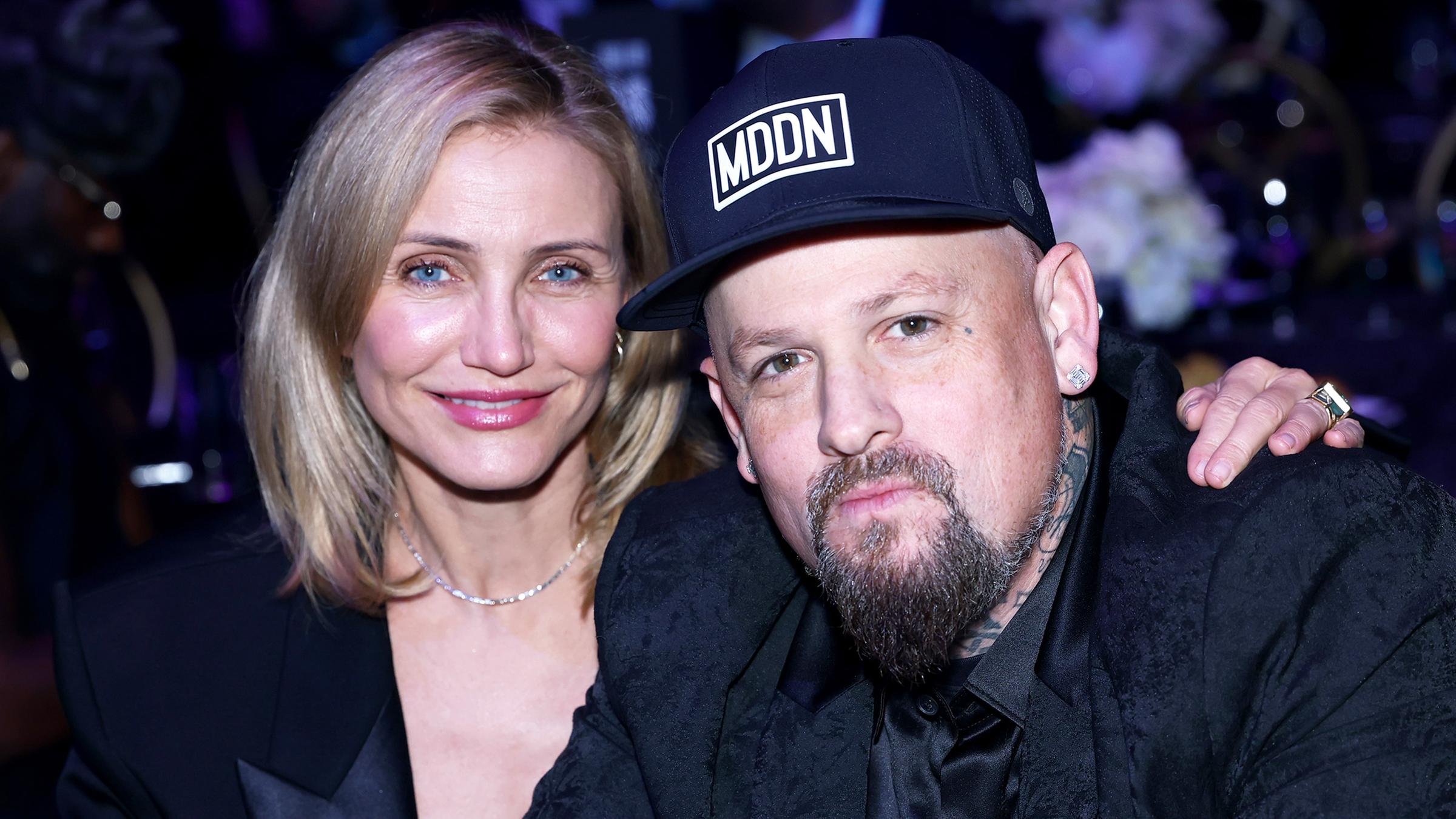 Cameron Diaz wie sie den Arm um ihren Ehemann Benji Madden legt und in die Kamera lächelt.