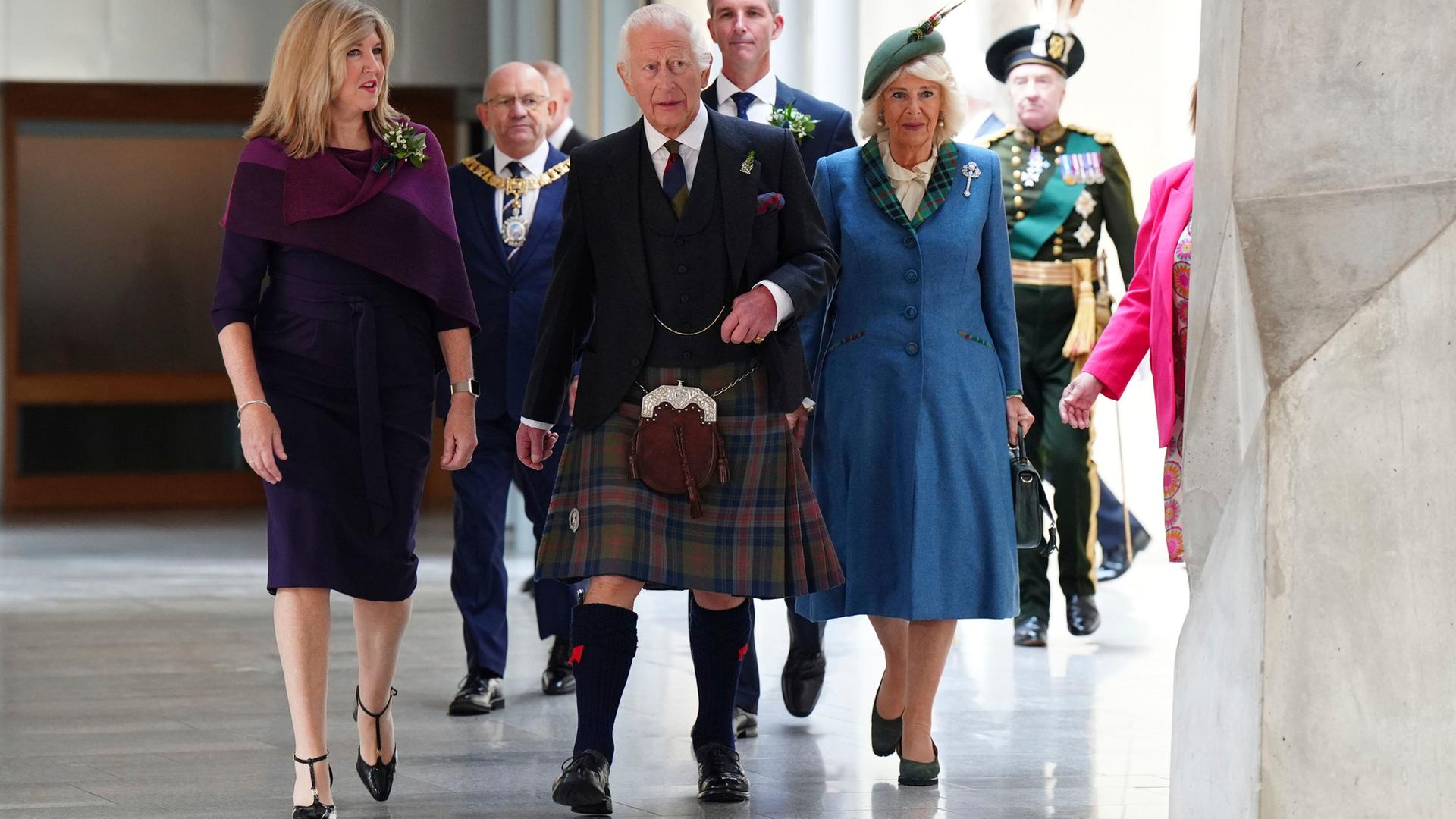 Camilla und Charles laufen im schottischen Parlament mit der Vorsitzenden Alison Johnson einen Gang entlang