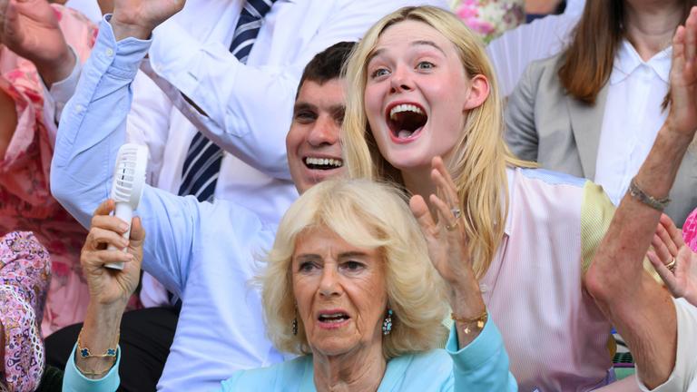 Die britische Königin Camilla ist jubelnd zu sehen, hinter ihr ist Elle Fanning ebenfalls jubelnd zu sehen.