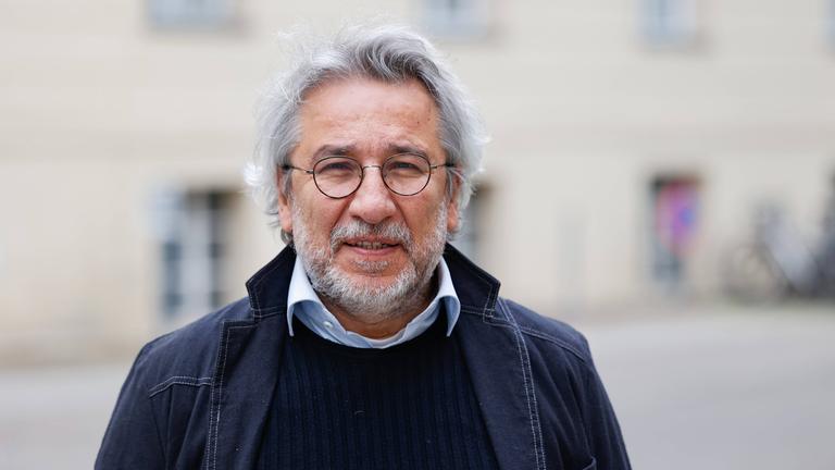 Foto eines Mannes mit weißen Locken, graumeliertem Bart und runder Metall-Brille.