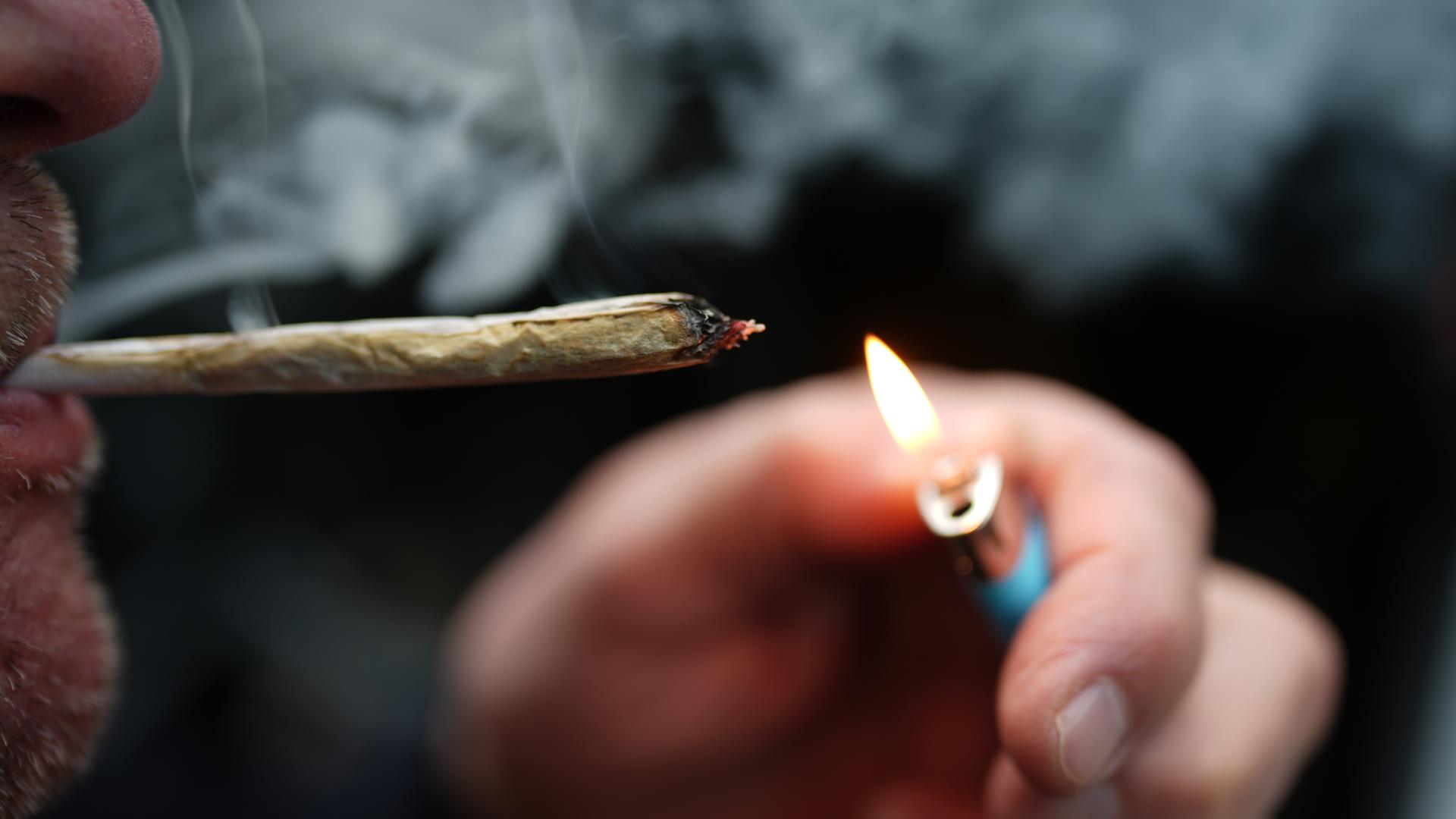 Archiv: Ein Mann zündet sich in einem Auto einen Joint an.