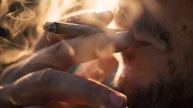 Ein Mann raucht einen Joint.