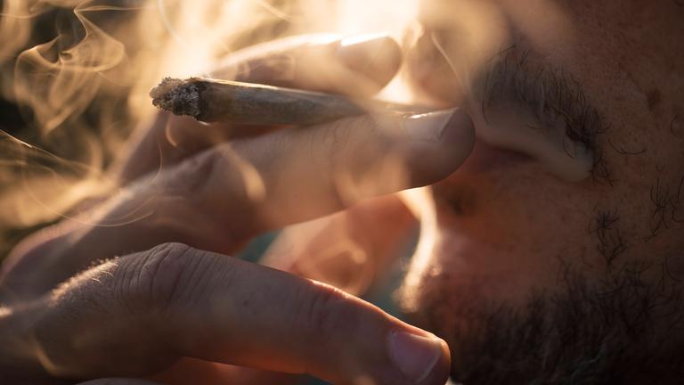 Ein Mann raucht einen Joint.