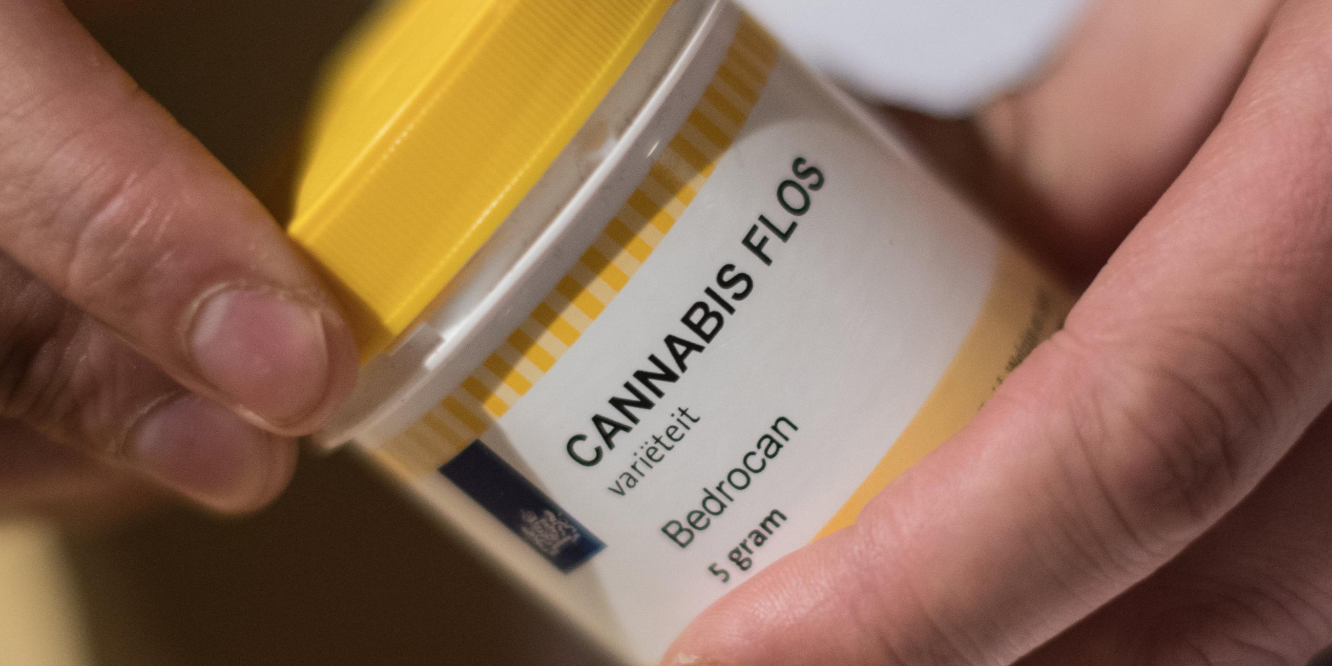 Ein Mann öffnet eine Dose mit Hanfblüten