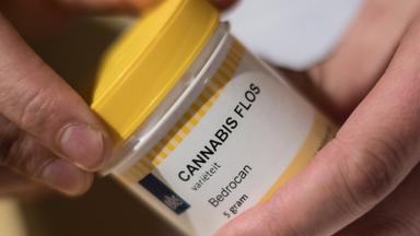 Ein Mann öffnet eine Dose mit Hanfblüten