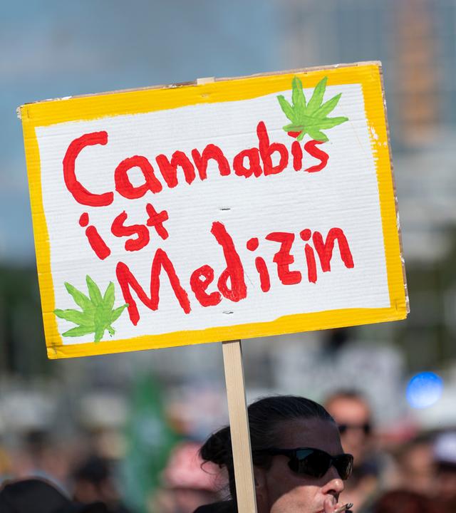 Ein Teilnehmer der Hanfparade 2026 unter dem Motto "Gerecht! Gesund! Genießen!" trägt ein Plakat mit der Aufschrift ÂCannabis ist Medizin