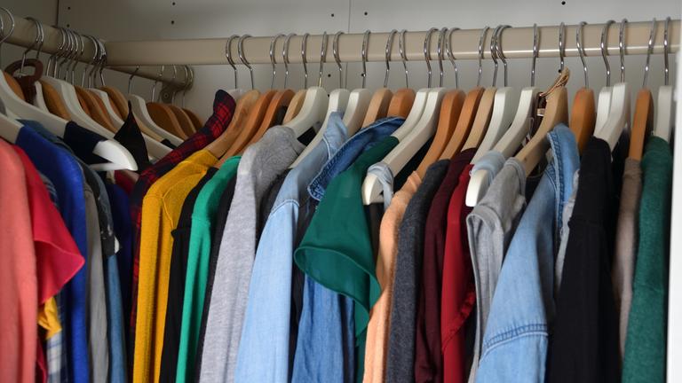 Der Inhalt eines Kleiderschranks mit Hemden auf Bügeln.