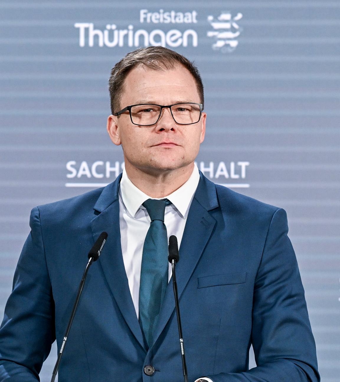 Carsten Schneider steht an einem Rednerpult und schaut in die Ferne.