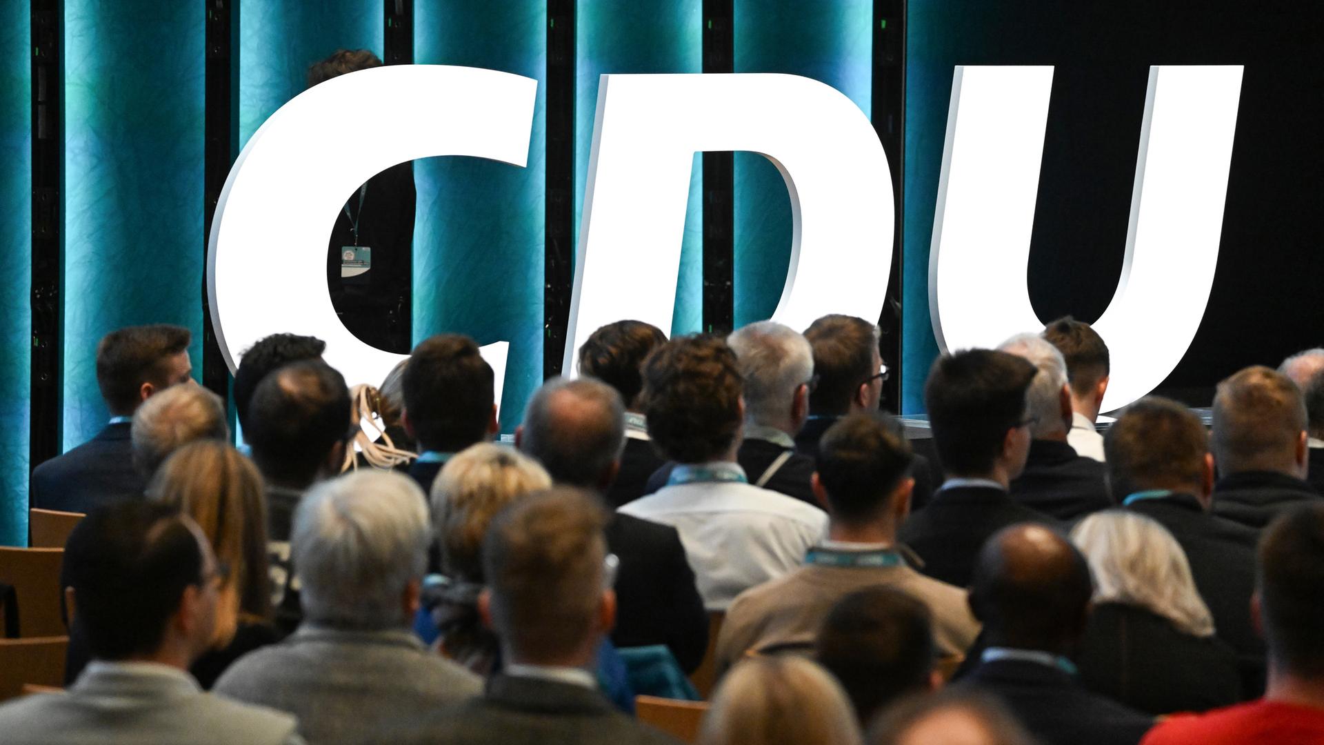 Baden-Württemberg, Stuttgart: Vor dem Schriftzug der Partei sitzen bei einer Grundsatzprogrammkonferenz der CDU in Baden-Württemberg Teilnehmer in der Carl Benz Arena in Stuttgart.