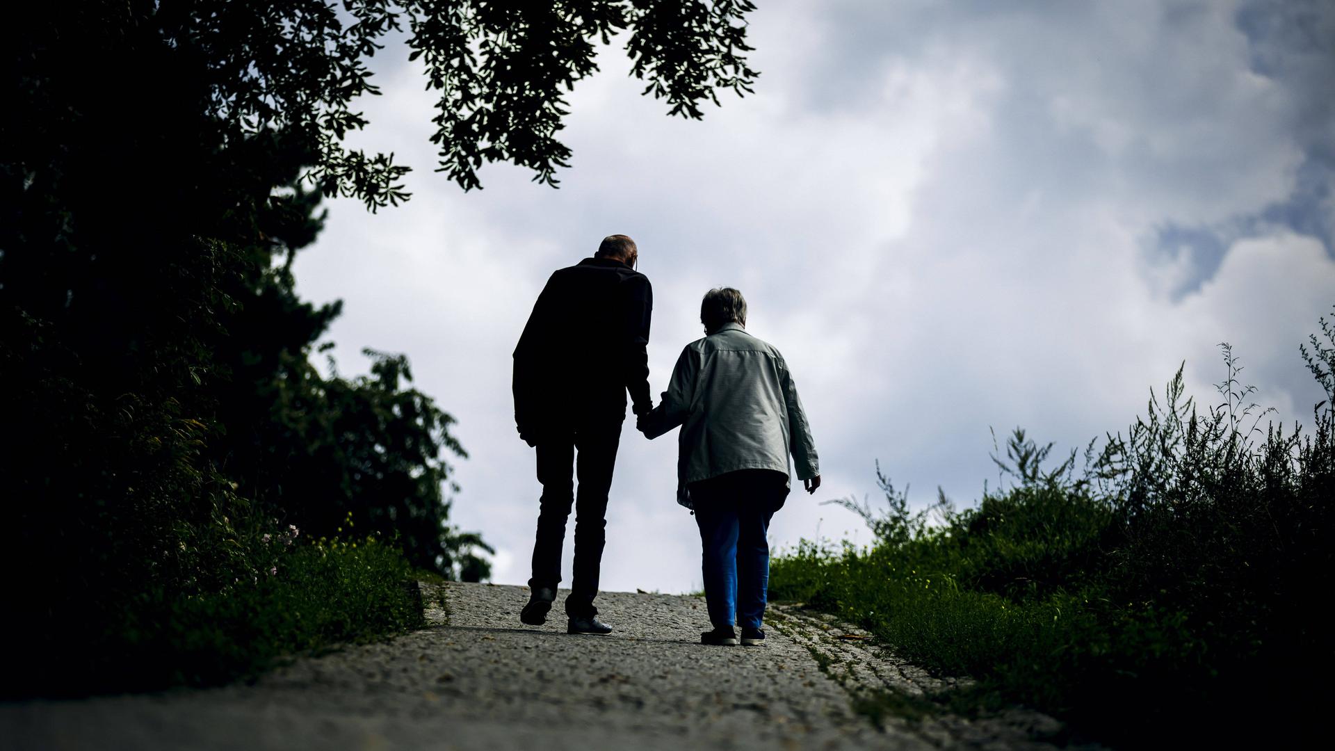 Ein altes Ehepaar laeuft bei einem Spaziergang gemeinsam einen Weg entlang am 30.08.2023 in Berlin.