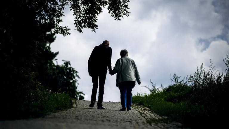 Ein altes Ehepaar laeuft bei einem Spaziergang gemeinsam einen Weg entlang am 30.08.2023 in Berlin.