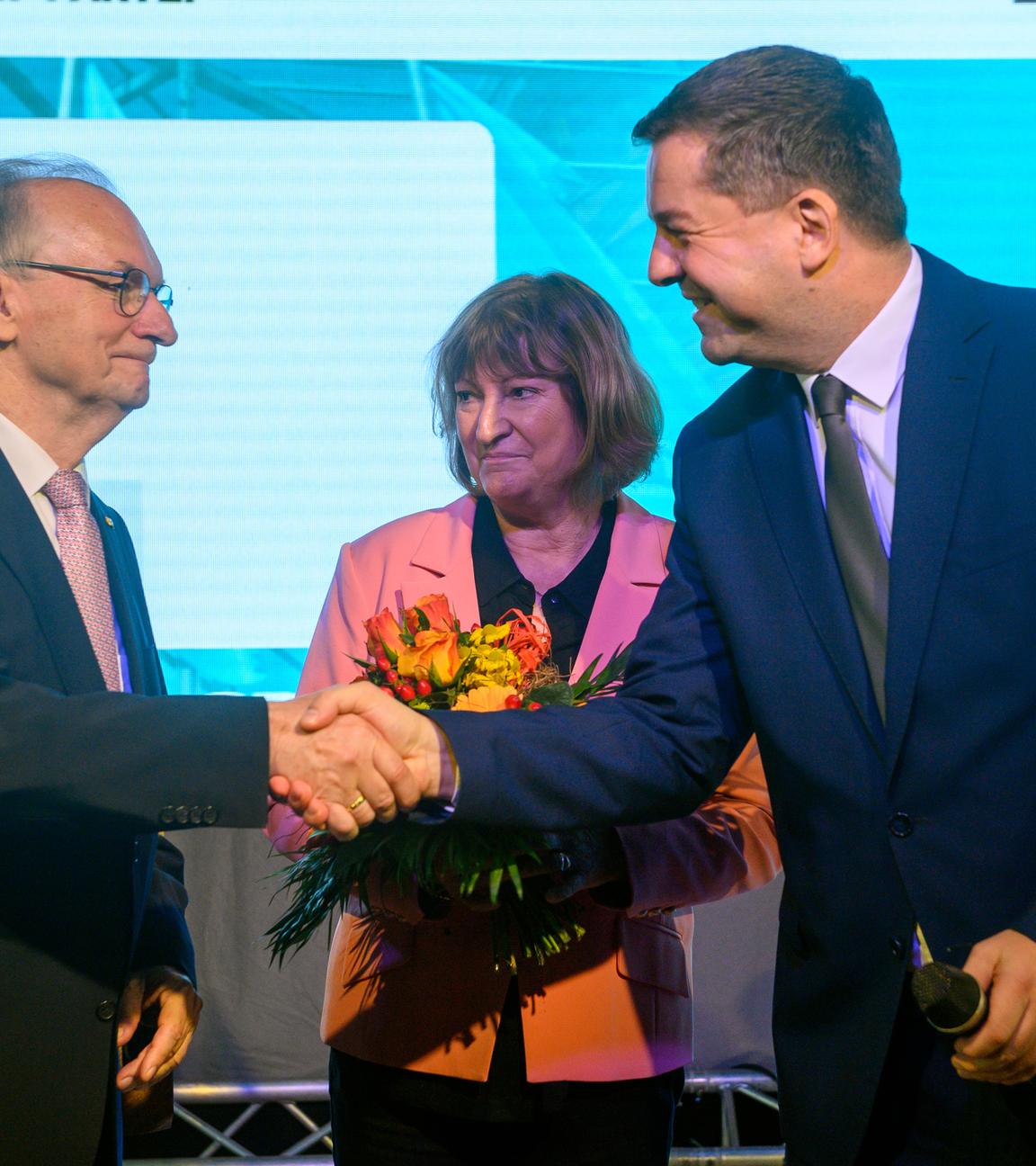 Reiner Haseloff (l-r, CDU), Ministerpräsident des Landes Sachsen-Anhalt und Ehefrau Gabriele Haseloff sowie Sven Schulze (CDU), Minister für Wirtschaft, Tourismus, Landwirtschaft und Forsten des Landes Sachsen-Anhalt stehen mit Blumen auf der Bühne der Landesvertreterversammlung der CDU und geben sich die Hände.
