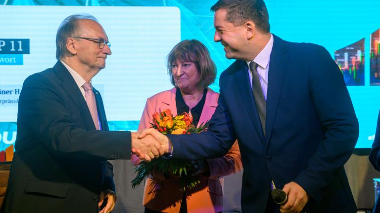 Reiner Haseloff (l-r, CDU), Ministerpräsident des Landes Sachsen-Anhalt und Ehefrau Gabriele Haseloff sowie Sven Schulze (CDU), Minister für Wirtschaft, Tourismus, Landwirtschaft und Forsten des Landes Sachsen-Anhalt stehen mit Blumen auf der Bühne der Landesvertreterversammlung der CDU und geben sich die Hände.