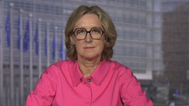 ZDF-Reporterin Susanne Freitag-Carteron in einer pinken Hemd-Jacke in dem Studio in Brüssel. Im Hintergrund sind EU-Flaggen zu sehen.