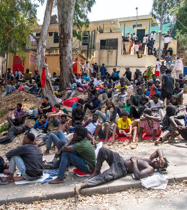 Migranten ruhen sich in Ceuta vor einem Zentrum aus, das für die vorübergehende Aufnahme von Einwanderern zuständig ist. 