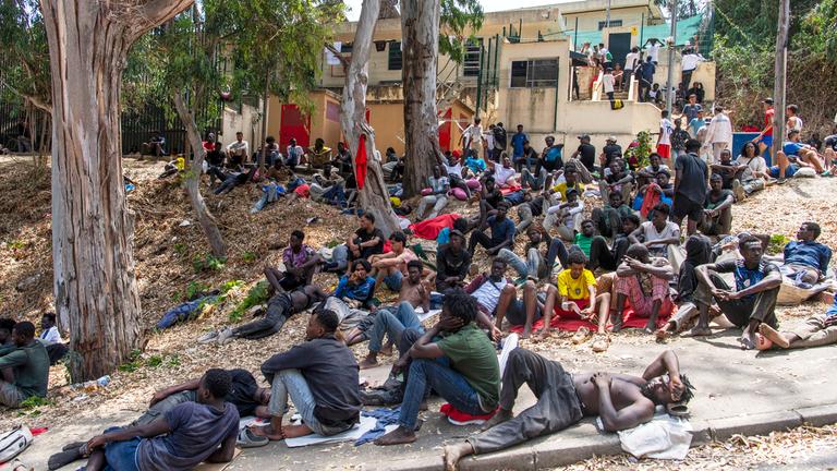 Migranten ruhen sich in Ceuta vor einem Zentrum aus, das für die vorübergehende Aufnahme von Einwanderern zuständig ist. 