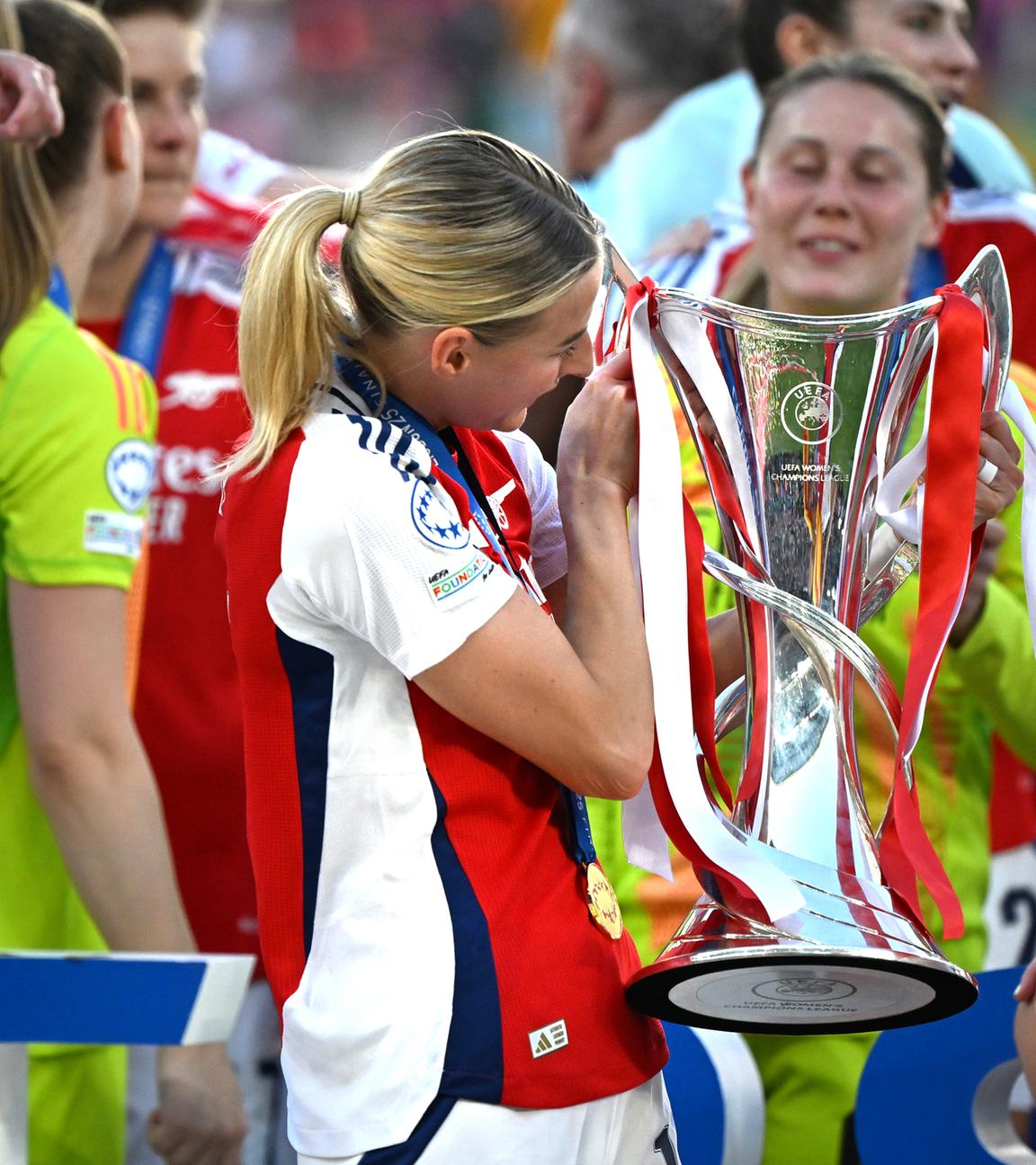 Eine Fußballspielerin des FC Arsenal hält den Champions League Pokal.